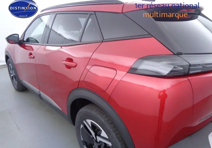 Vue 3/4 arrière gauche d'un Peugeot 2008 rouge Elixir Metal avec toit noir et jantes bi-ton.
