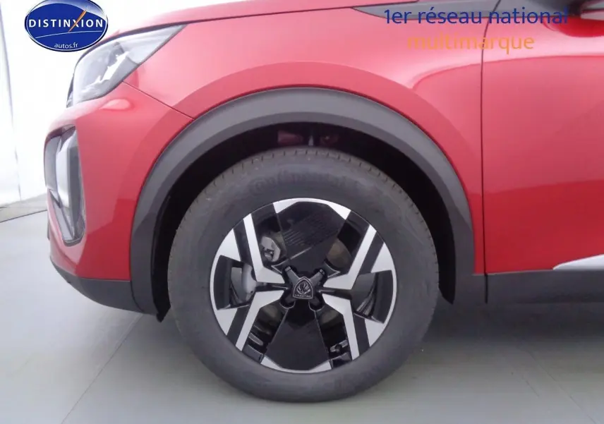 Gros plan sur la roue avant gauche du Peugeot 2008 rouge Elixir Metal avec jante bi-ton noire et argentée.