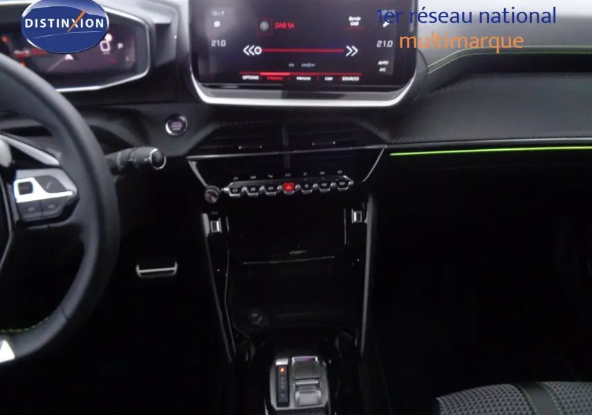 Vue intérieure centrée sur la console et le tableau de bord du Peugeot 2008 gris avec détails verts et écran tactile.