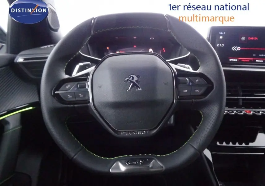 Volant cuir noir avec surpiqûres vertes du Peugeot 2008 GT 2023, tableau de bord numérique et écran tactile visible.