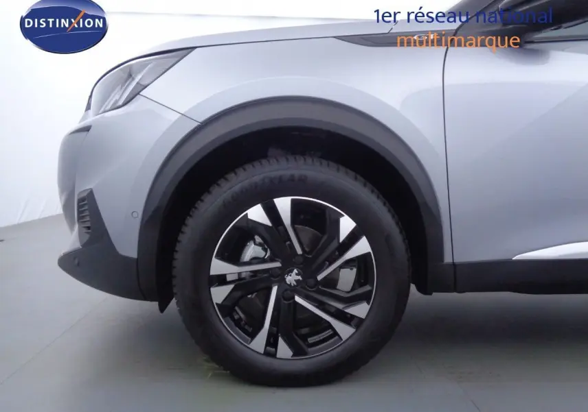 Gros plan sur la roue avant gauche d’un Peugeot 2008 gris Artense métal avec jante noire et argentée.