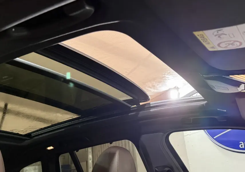 Toit ouvrant panoramique ouvert montrant l'intérieur noir d'un BMW X3 bleu 2023 côté gauche.