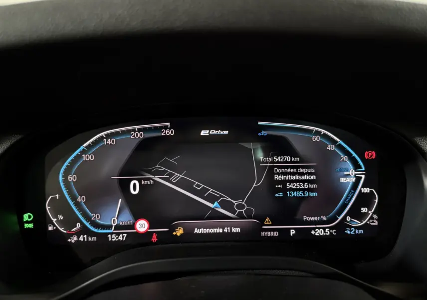 Tableau de bord numérique du BMW X3 xDrive30e 2023 affichant la vitesse, autonomie et navigation en mode hybride.