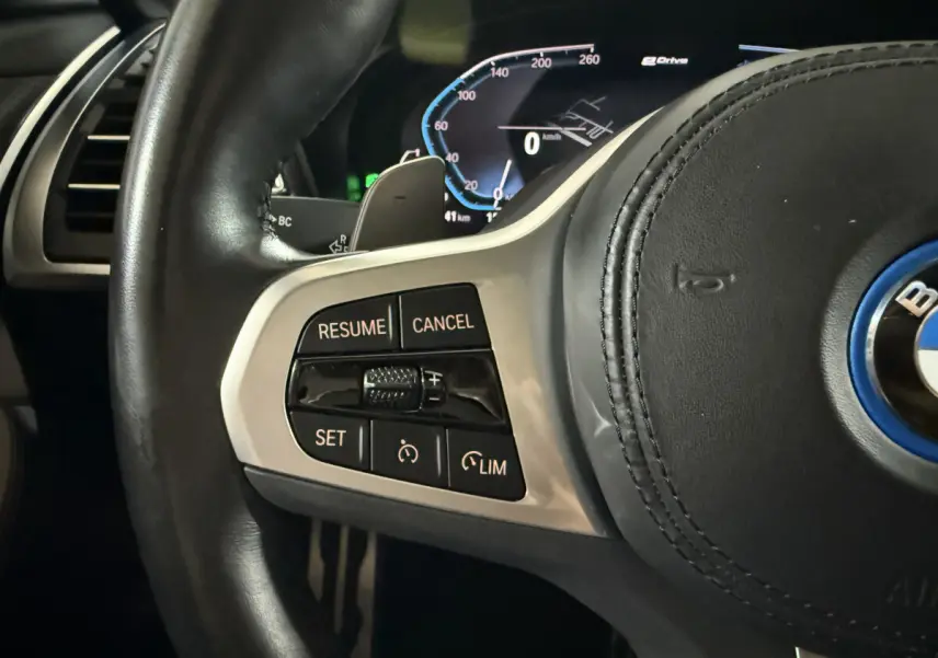 Gros plan sur le volant cuir noir de la BMW X3 xDrive30e 2023, avec commandes de régulateur de vitesse à gauche.