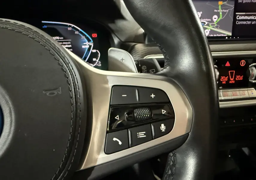 Gros plan sur les commandes au volant côté droit du BMW X3 bleu 2023 avec affichage digital et écran tactile.