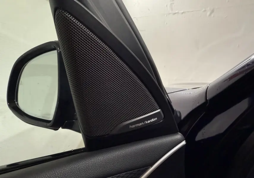 Gros plan sur l'enceinte Harman/Kardon et le rétroviseur côté gauche d'une BMW X3 bleu foncé 2023.