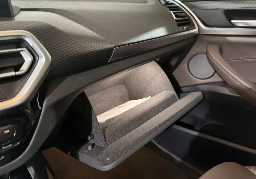 Vue intérieure côté passager du BMW X3 xDrive30e 2023, boîte à gants ouverte et garniture marron visible
