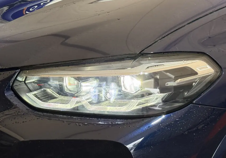 Gros plan sur le phare avant droit d'un BMW X3 xDrive30e bleu, mettant en valeur ses LED et détails modernes.