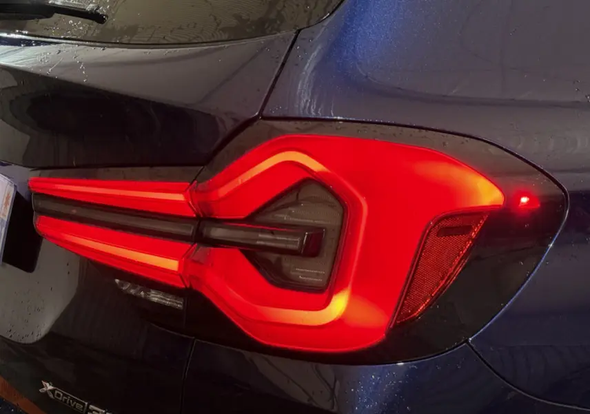 Gros plan sur le feu arrière droit rouge vif du BMW X3 xDrive30e bleu 2023, soulignant son design lumineux distinctif.
