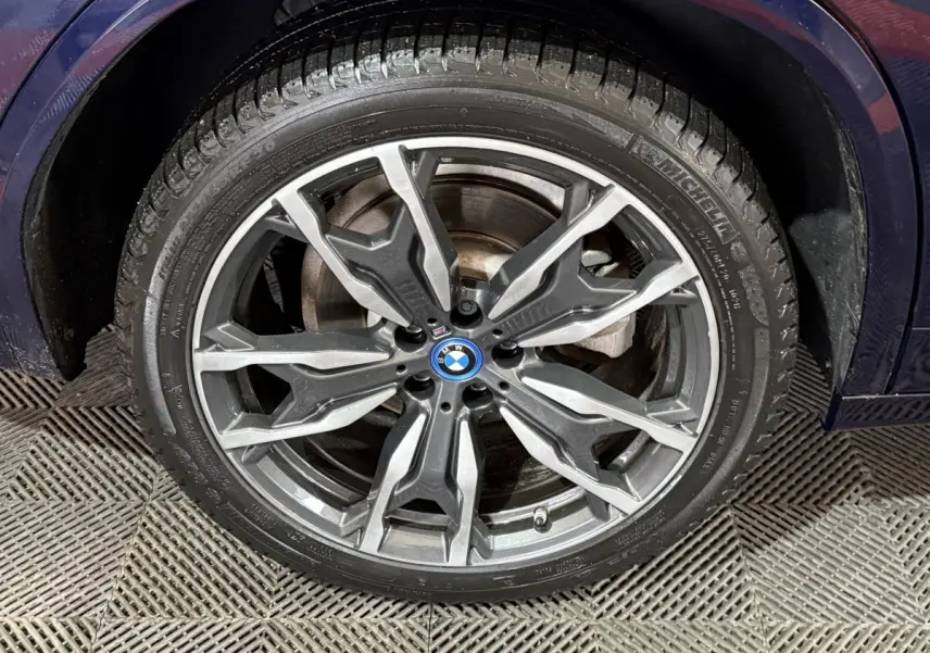 Gros plan sur la jante alliage grise du BMW X3 xDrive30e bleu, montrant le logo central et le pneu Michelin.