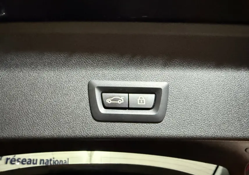 Boutons d'ouverture et de verrouillage du coffre sur le panneau intérieur d'un BMW X3 bleu hybride rechargeable.