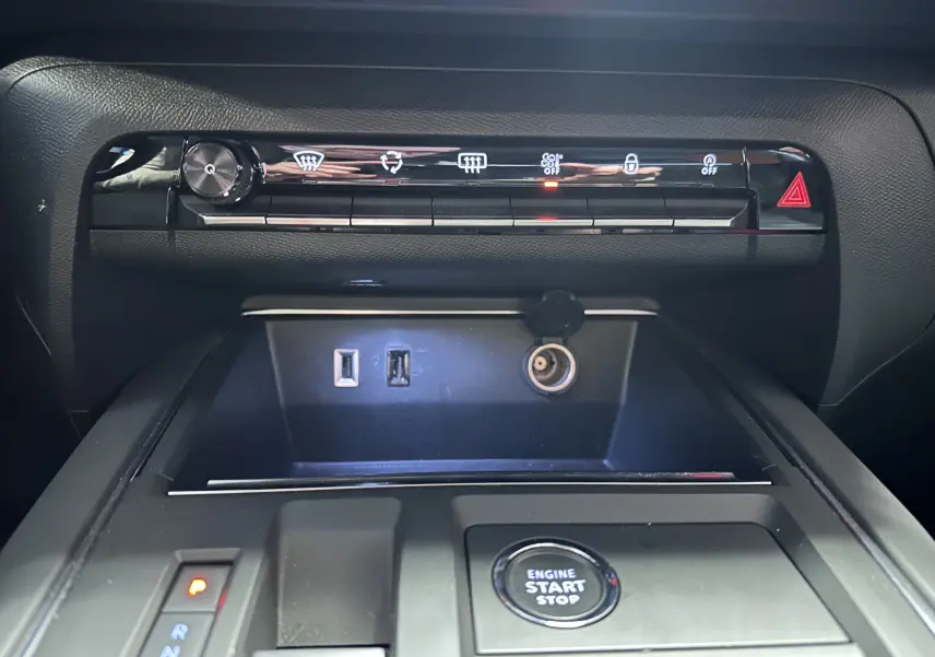 Vue rapprochée de la console centrale du Citroën C5 Aircross hybride noir 2025, avec boutons de contrôle, ports USB et bouton start/stop.