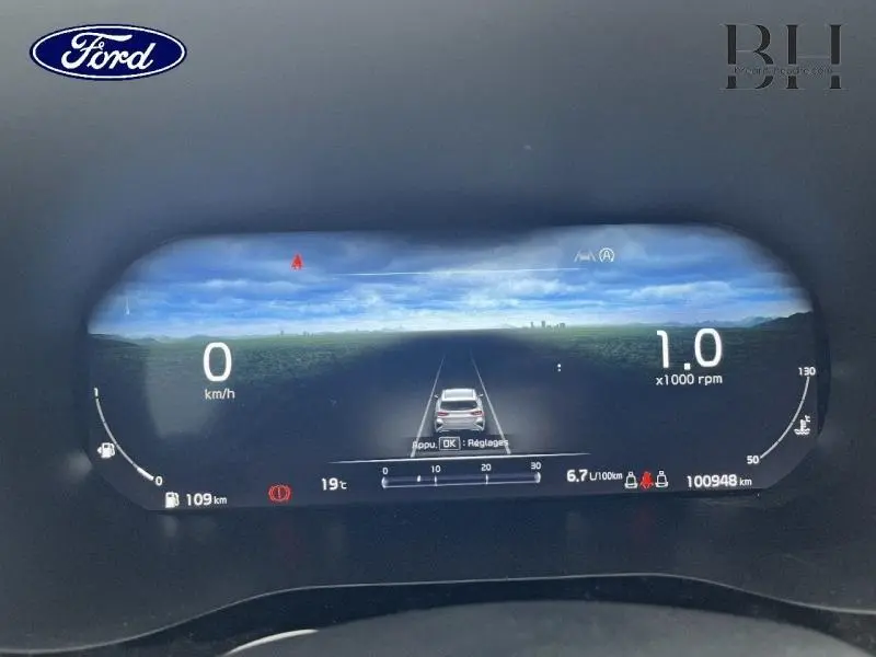 Tableau de bord numérique Ford affichant vitesse, régime moteur et assistance à la conduite, vue frontale rapprochée.