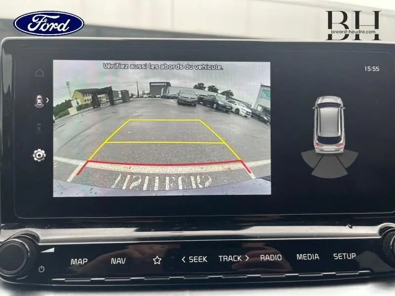 Écran tactile affichant la caméra de recul et les capteurs de stationnement d'une Kia CEE'D noire vue de l'arrière.