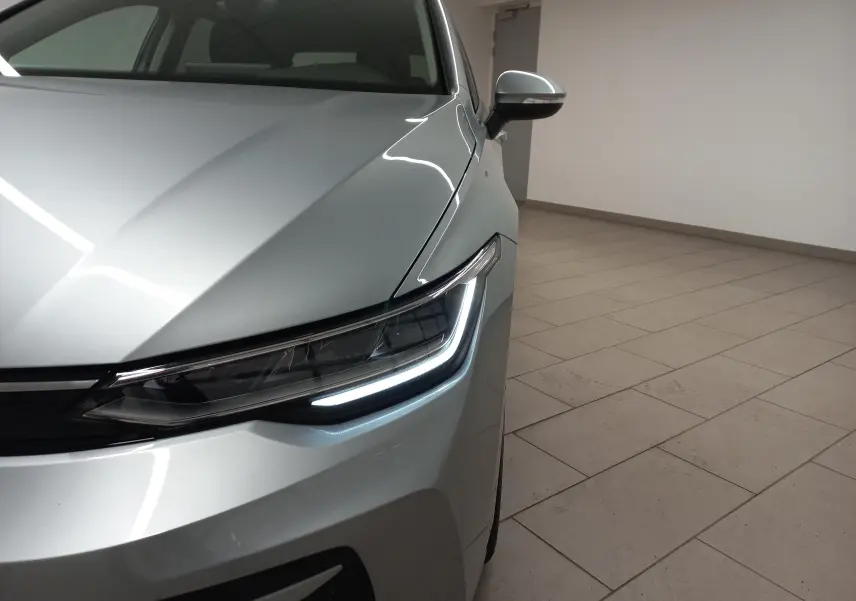 Gros plan sur l'avant droit d'une Volkswagen Golf 1.5 eTSI 2025 en Argent Dolomite avec feux LED allumés.