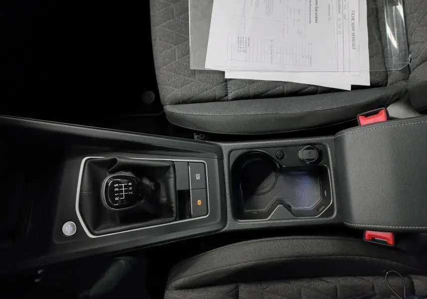 Vue plongeante sur la console centrale de la Volkswagen Golf 1.5 eTSI 116 BVM6, avec levier de vitesses manuel et porte-gobelets.