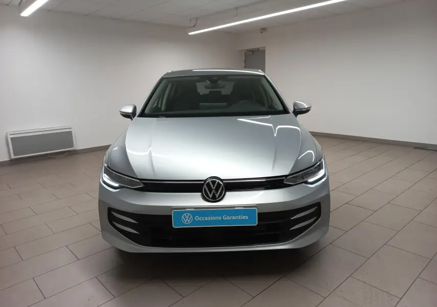 Vue frontale d'une Volkswagen Golf 1.5 eTSI 116 BVM6 VW Edition en argent Dolomite avec phares LED allumés.