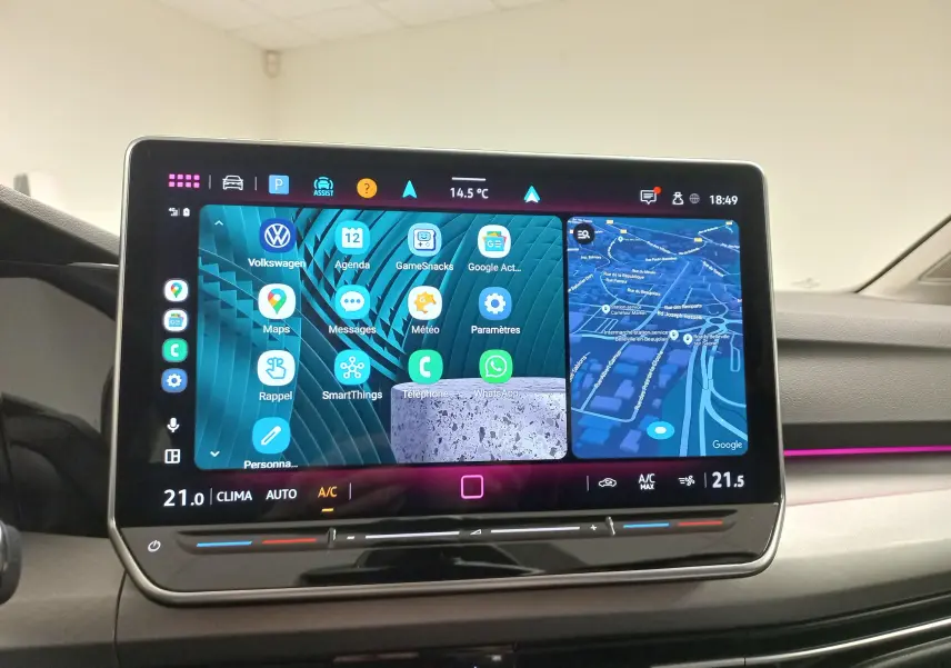 Vue intérieure du tableau de bord de la Volkswagen Golf 1.5 eTSI 2025 avec écran tactile multimédia et ambiance lumineuse rose.