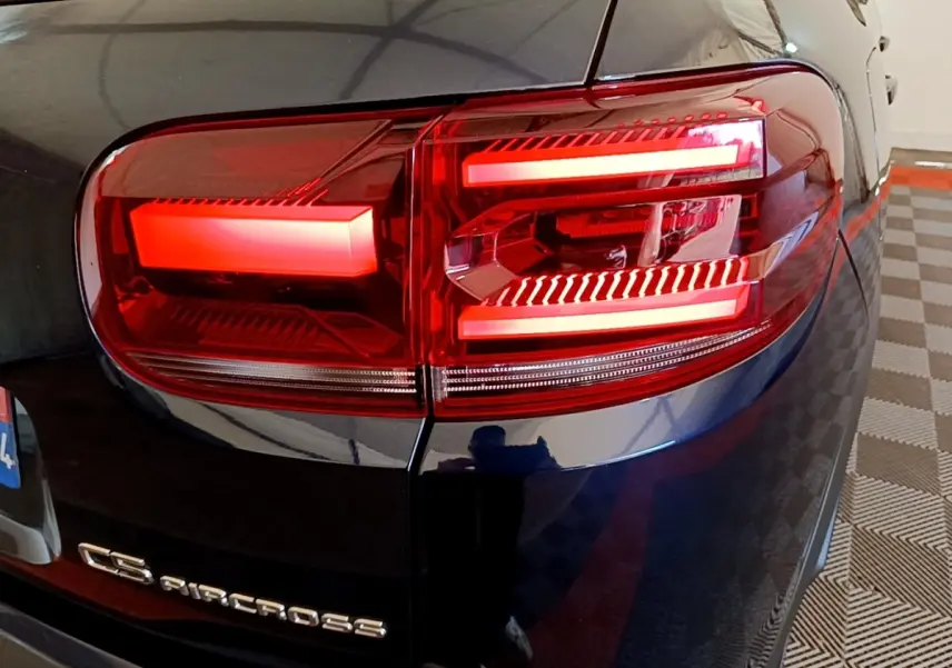 Gros plan sur le feu arrière droit rouge du Citroën C5 Aircross 2023 couleur sombre, avec logo visible sur la malle arrière.