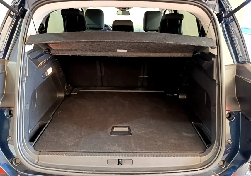 Coffre ouvert arrière d’un Citroën C5 Aircross 2023 bleu foncé avec tablette cache-bagages et sièges noirs visibles.