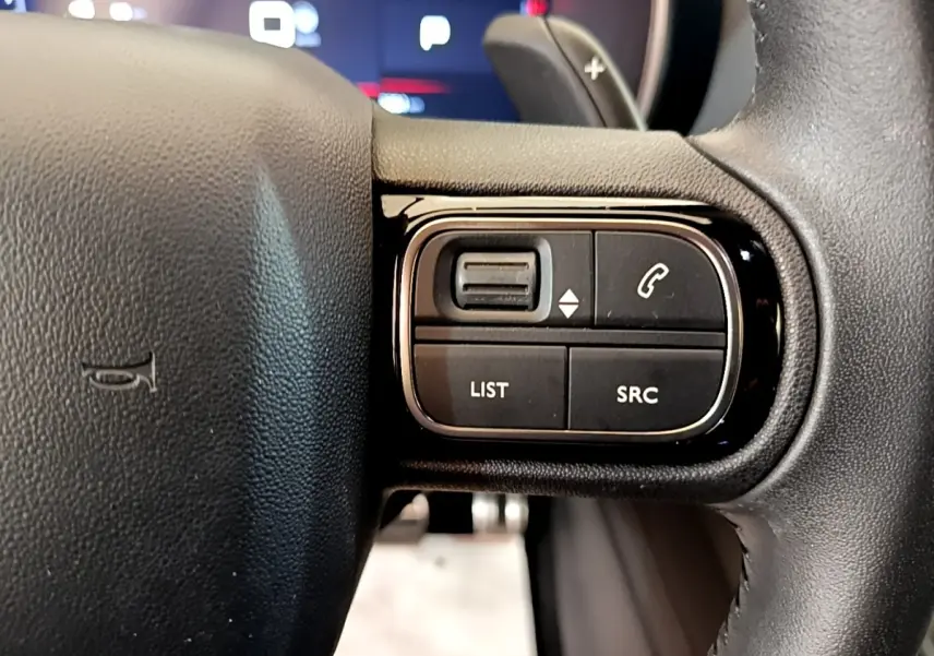 Gros plan sur les commandes gauche du volant noir du Citroën C5 Aircross 2023, boutons LIST et SRC visibles.