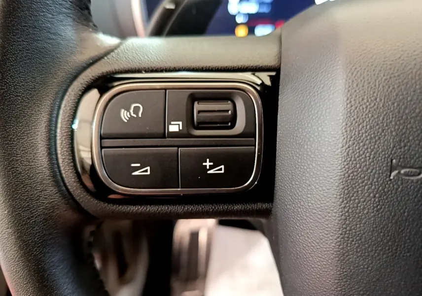 Gros plan sur les commandes multifonctions noires à gauche du volant cuir noir du Citroën C5 Aircross 2023.