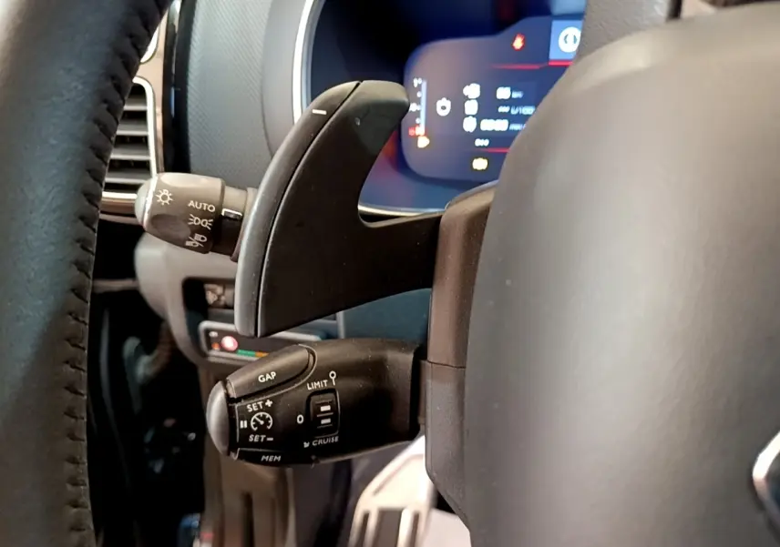 Gros plan sur la commande multifonction du volant côté gauche du Citroën C5 Aircross 2023, affichage digital en arrière-plan.