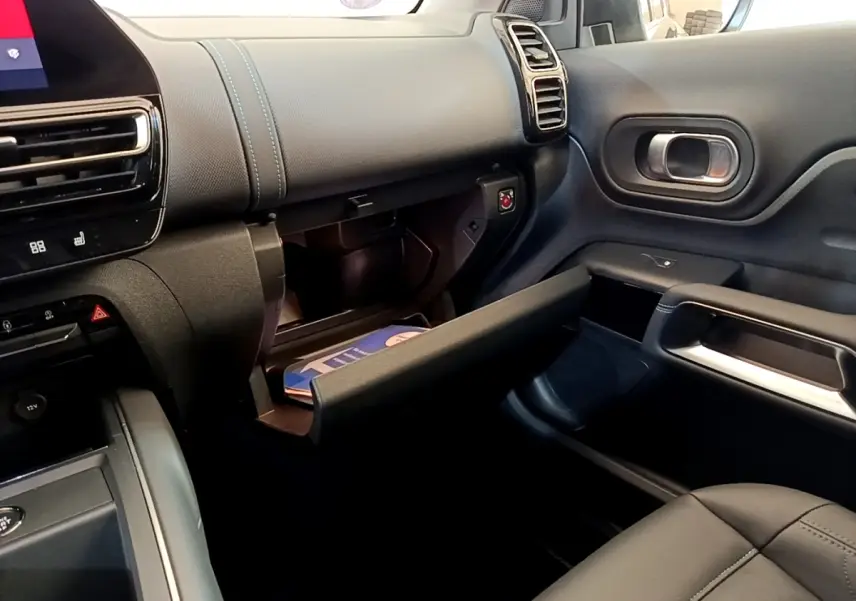Vue intérieure côté passager du tableau de bord noir avec boîte à gants ouverte et coutures bleues sur Citroën C5 Aircross 2023.