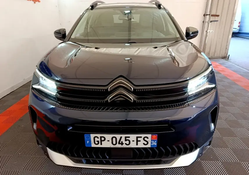 Vue avant d'un Citroën C5 Aircross 2023 bleu foncé avec feux LED allumés et calandre distinctive double chevron.