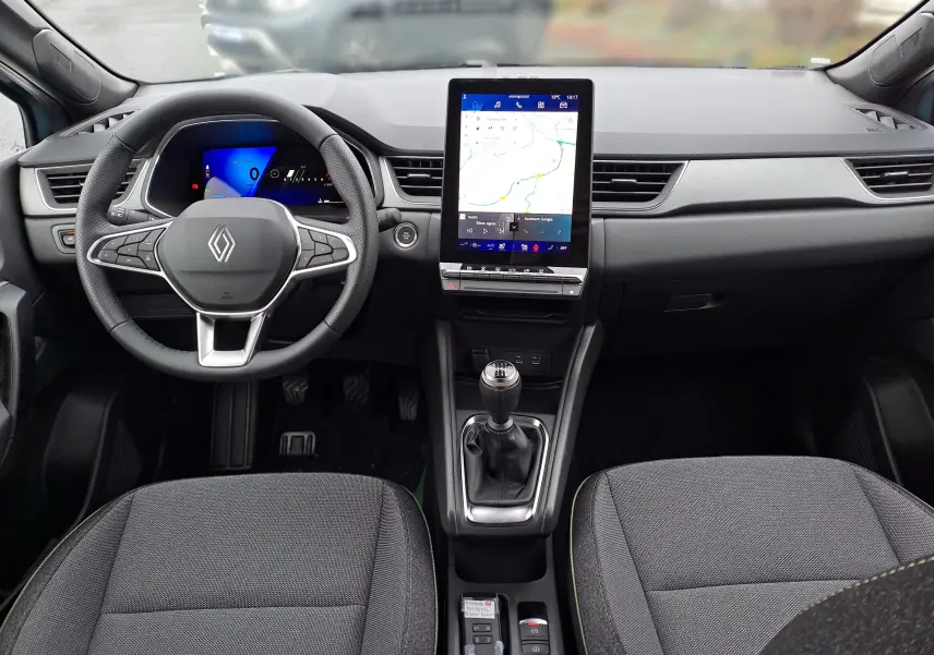 Vue intérieure avant du Renault Symbioz 2025, tableau de bord noir avec écran tactile vertical et levier de vitesses manuel.