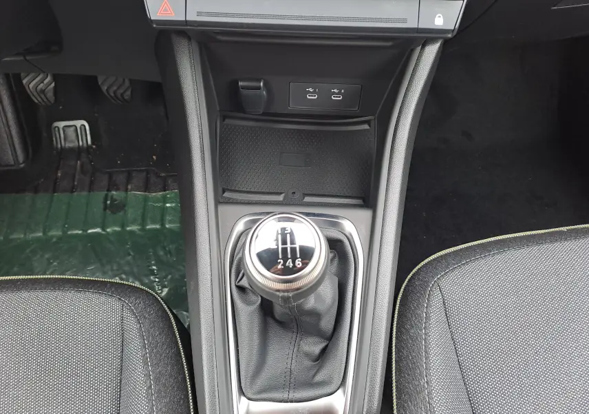 Vue plongeante sur la console centrale d'une Renault Symbioz bleu mercure, mettant en valeur le levier de vitesse manuel et les ports USB.