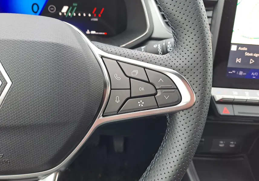 Gros plan sur le côté droit du volant perforé noir du Renault Symbioz bleu Mercure, avec commandes multifonctions visibles.