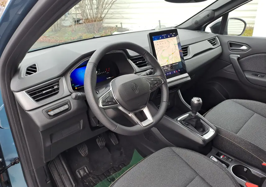 Vue intérieure côté conducteur du Renault Symbioz bleu Mercure, avec volant multifonction et écran tactile vertical.