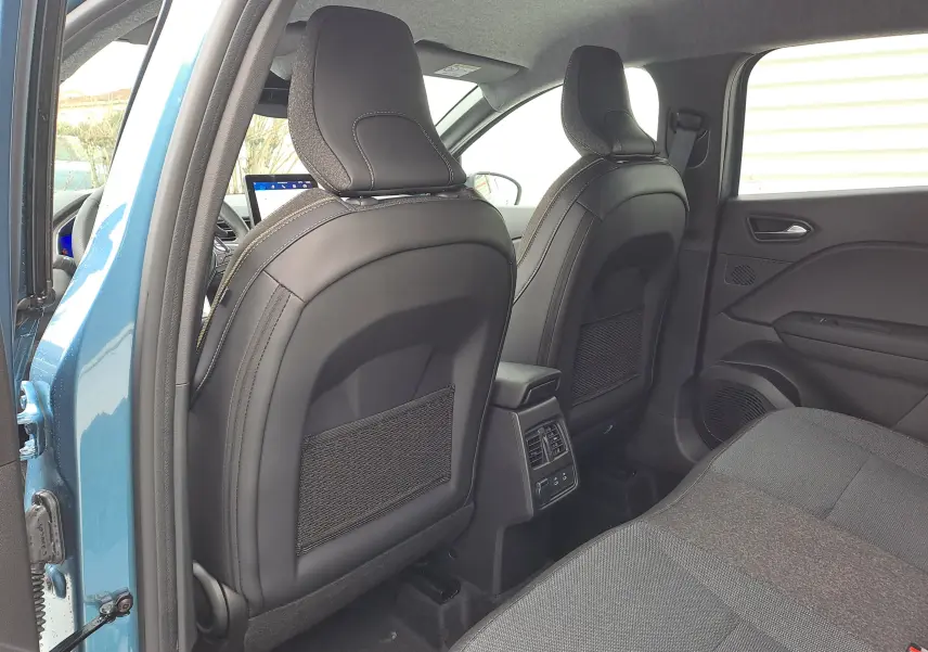 Vue intérieure arrière du Renault Symbioz bleu mercure 2025, montrant les dossiers noirs des sièges avant et la banquette tissu arrière.