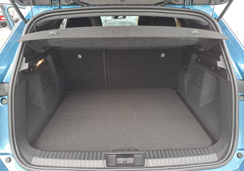 Vue arrière du coffre ouvert du Renault Symbioz bleu mercure, montrant un espace de chargement propre et spacieux.