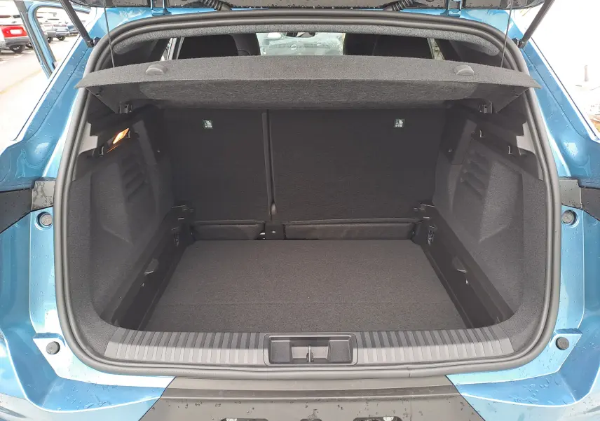 Coffre ouvert vu de l'arrière d'une Renault Symbioz bleu mercure, montrant un espace de chargement propre et spacieux.