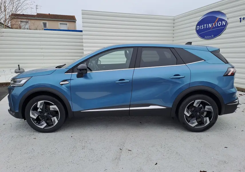 Profil latéral droit d’un Renault Symbioz bleu mercure 2025, avec jantes bicolores et lignes chromées distinctives.