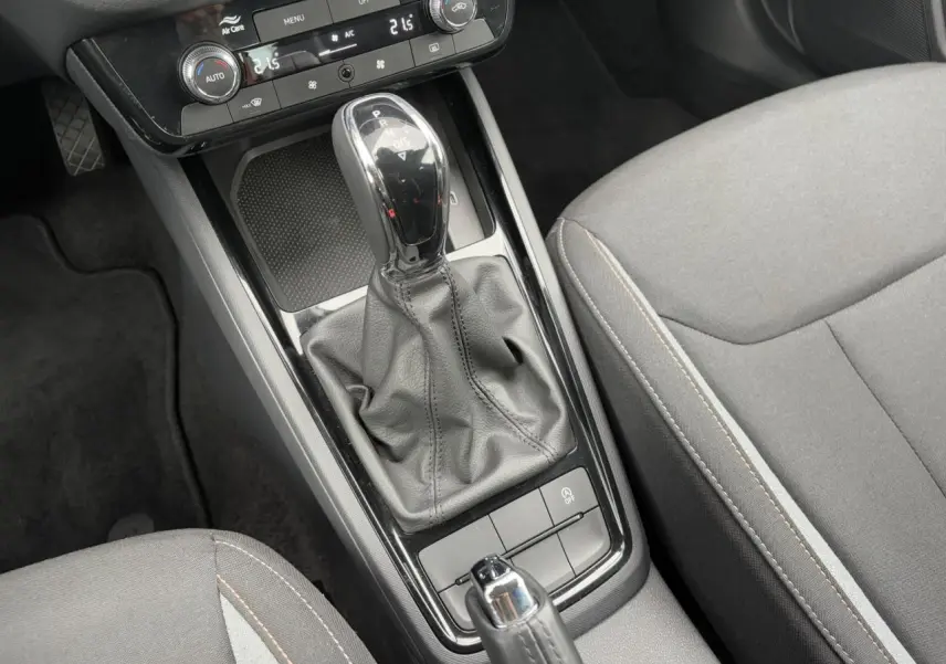 Gros plan sur la console centrale de la Skoda Scala 2024 avec levier de boîte auto et sièges gris à surpiqûres.