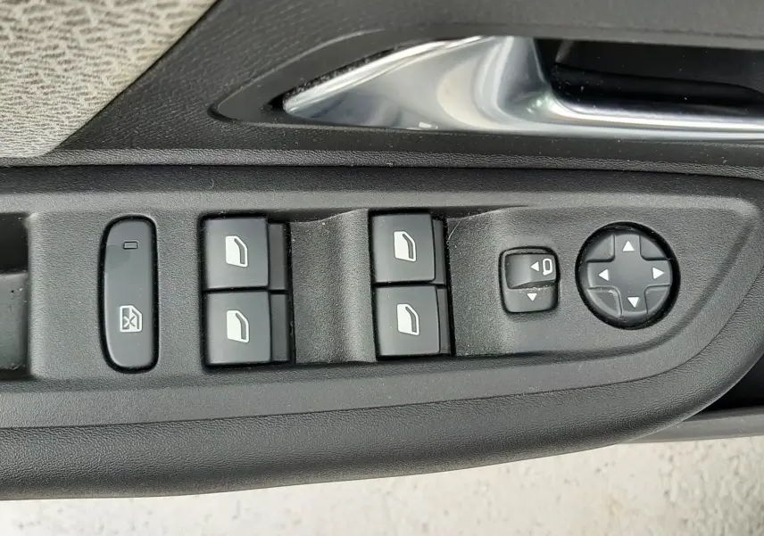 Gros plan sur les commandes de lève-vitres et réglages des rétroviseurs côté conducteur d'une Citroën C4 gris acier 2024.