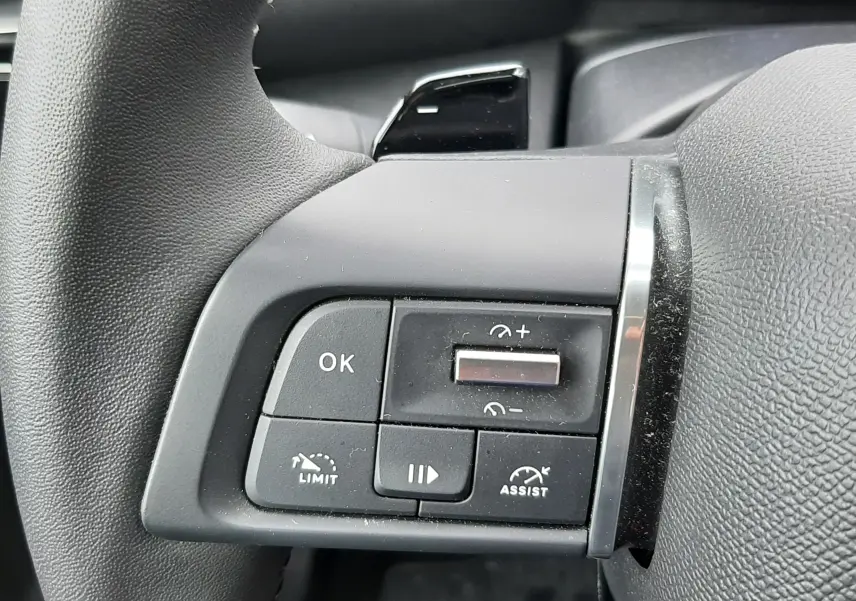 Gros plan sur les commandes au volant côté gauche de la Citroën C4 Hybrid 136 gris acier, boutons de limitation et assistance visibles.