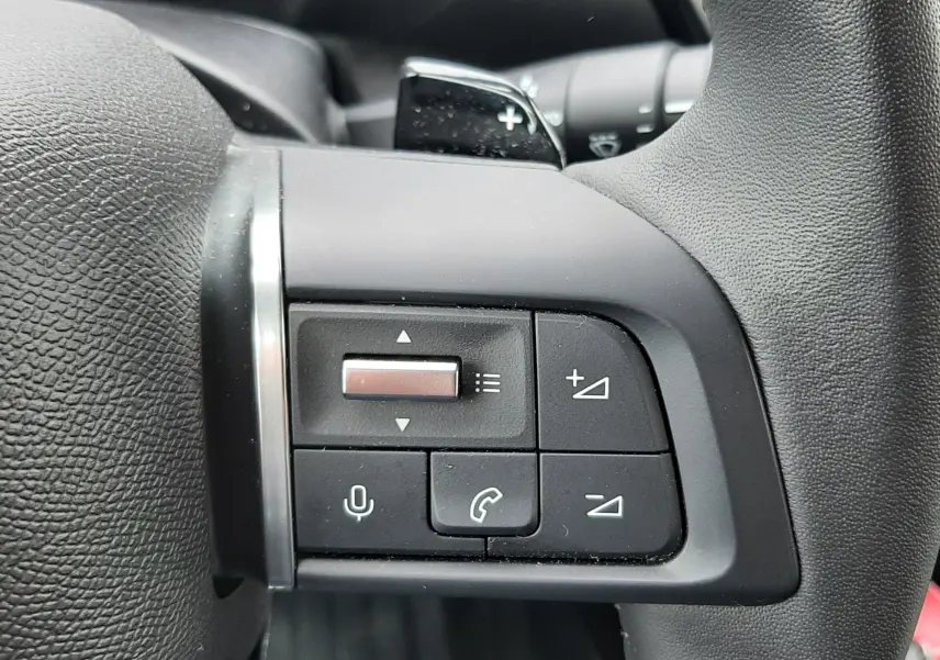 Gros plan sur les commandes multifonctions au volant du Citroën C4 Hybrid 136 gris acier, côté gauche.