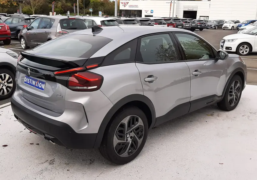 Vue 3/4 arrière droite d'une Citroën C4 Hybrid 136 gris acier avec toit noir et feux arrière LED distinctifs.