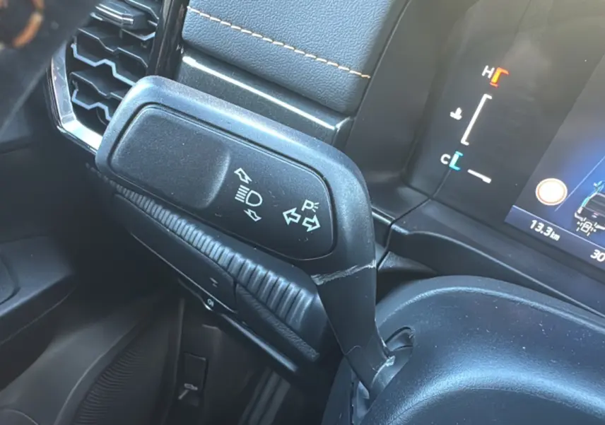 Gros plan sur la manette de clignotants à gauche du volant dans l'habitacle du Ford Ranger gris carbone 2025.