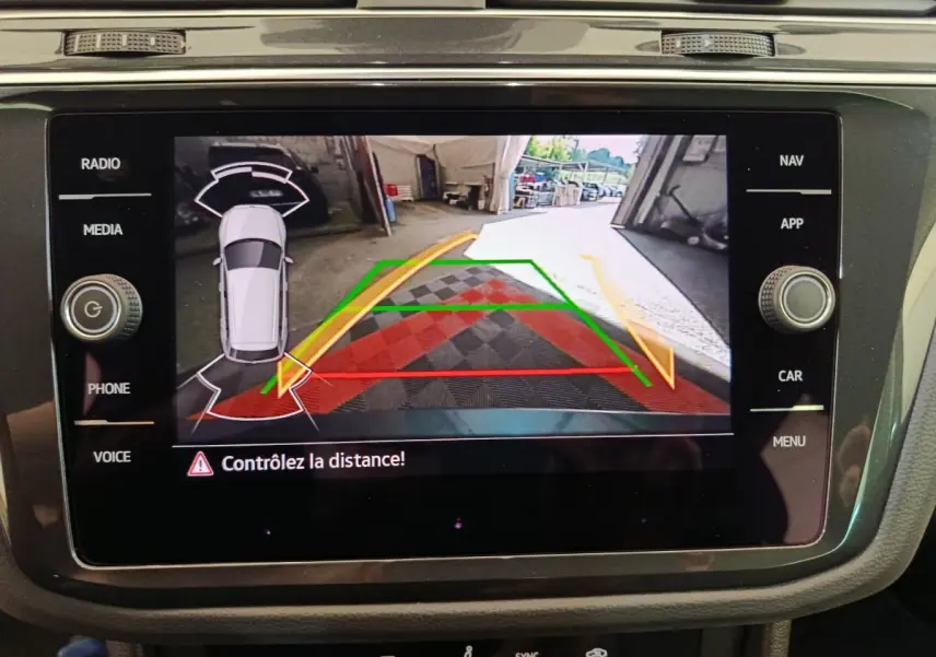 Écran tactile central du Volkswagen Tiguan bleu 2022 montrant la caméra de recul avec guidage de trajectoire coloré.