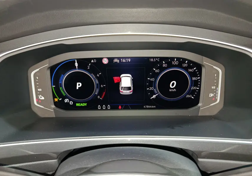 Tableau de bord numérique du Volkswagen Tiguan hybride bleu, affichant la vitesse à 0 km/h et porte avant gauche ouverte.