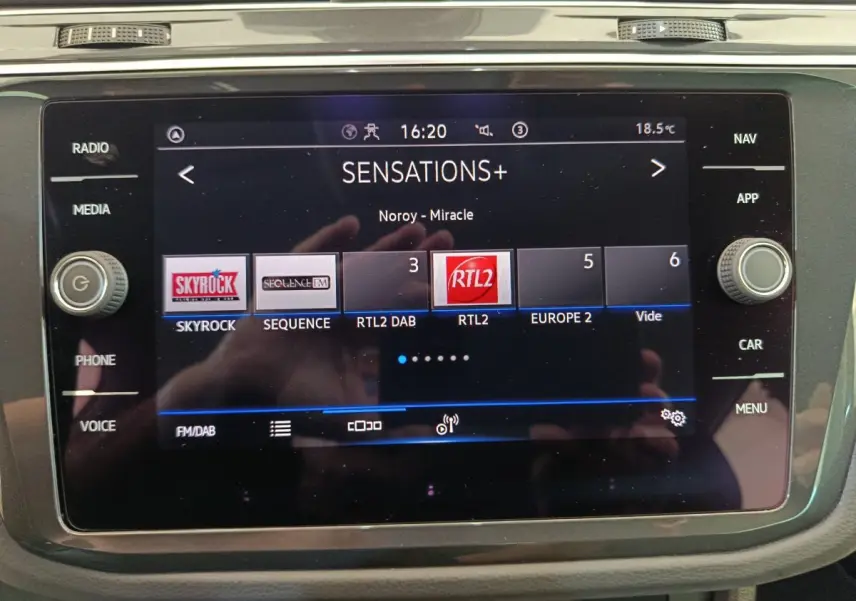 Écran tactile central du Volkswagen Tiguan bleu 2022 affichant la radio avec plusieurs stations FM/DAB visibles.