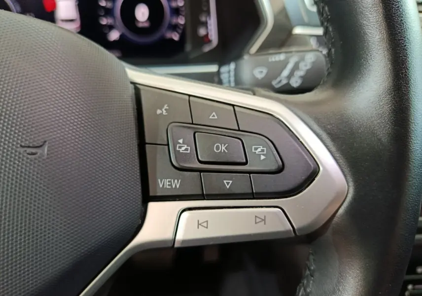 Gros plan sur les commandes du volant cuir noir du Volkswagen Tiguan 2022, boutons multifonctions et affichage digital.