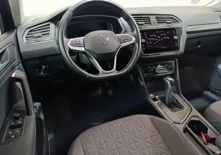 Intérieur noir du Volkswagen Tiguan 2022, vue du poste de conduite avec volant cuir et écran tactile central.