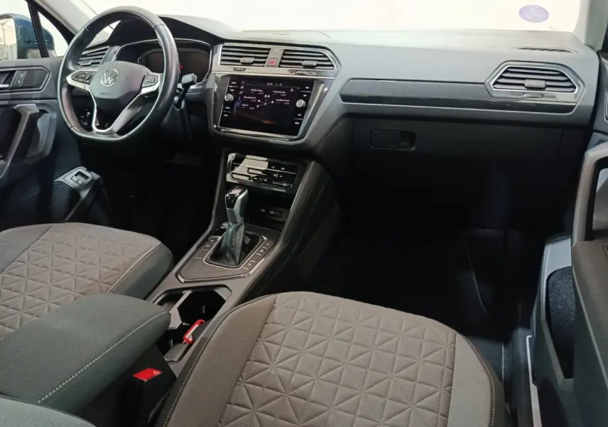 Intérieur avant droit du Volkswagen Tiguan bleu 2022, tableau de bord moderne avec écran tactile et volant multifonctions.