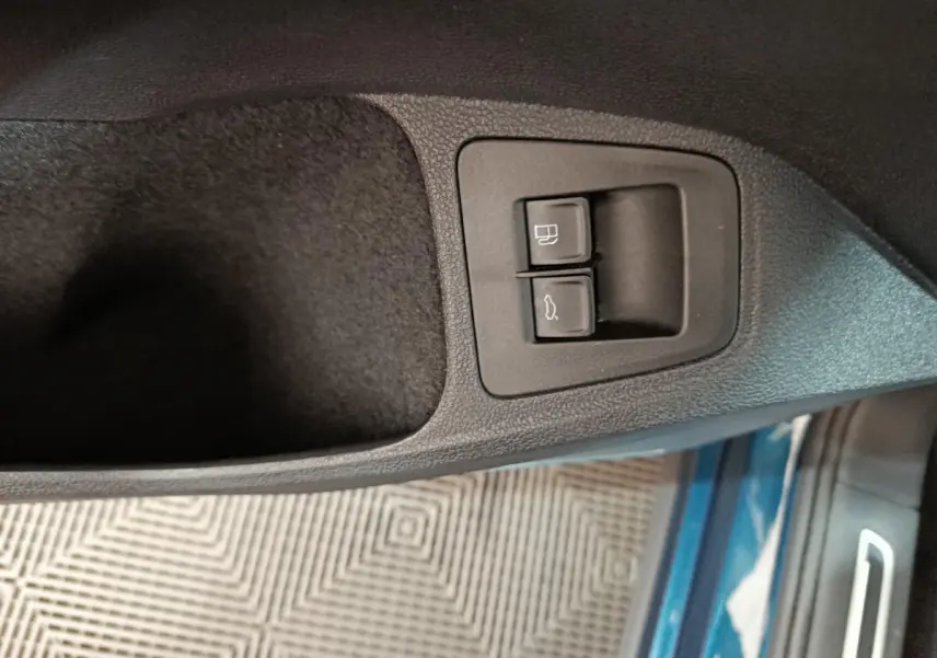 Gros plan sur les commandes d'ouverture du coffre et du bouchon de carburant côté conducteur du Volkswagen Tiguan bleu 2022.
